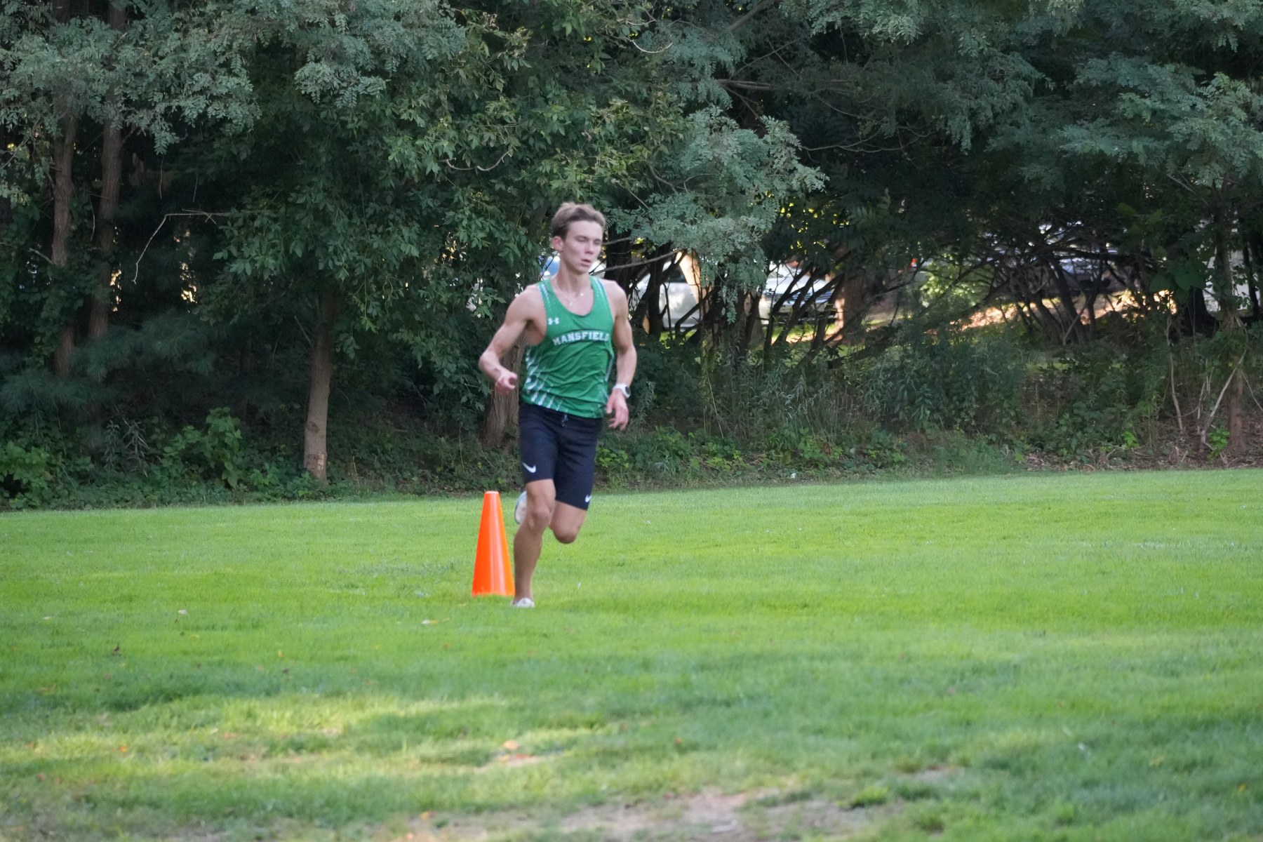 A Mansfield runner rounding an orange cone on the grass.